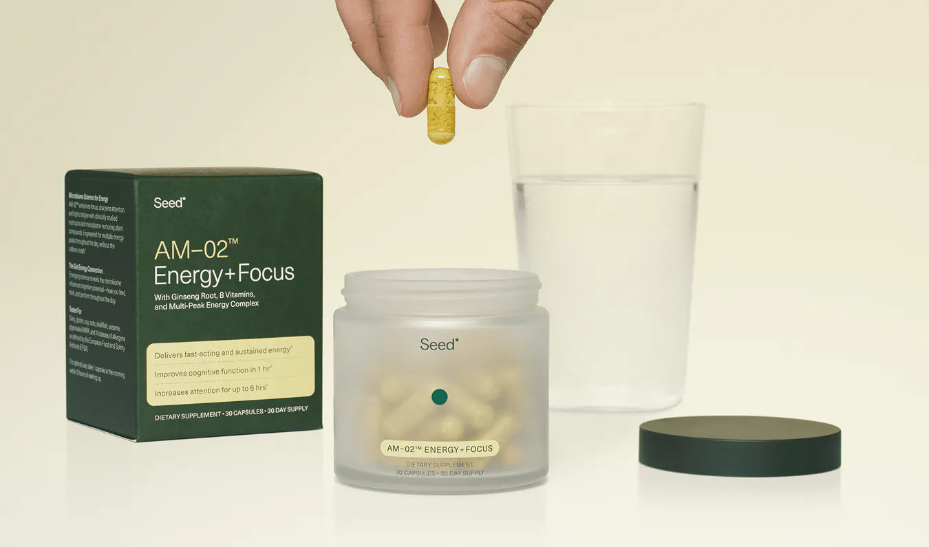 Seed AM-02 Energy + Focus supplement with packaging and a pill being held above a glass.